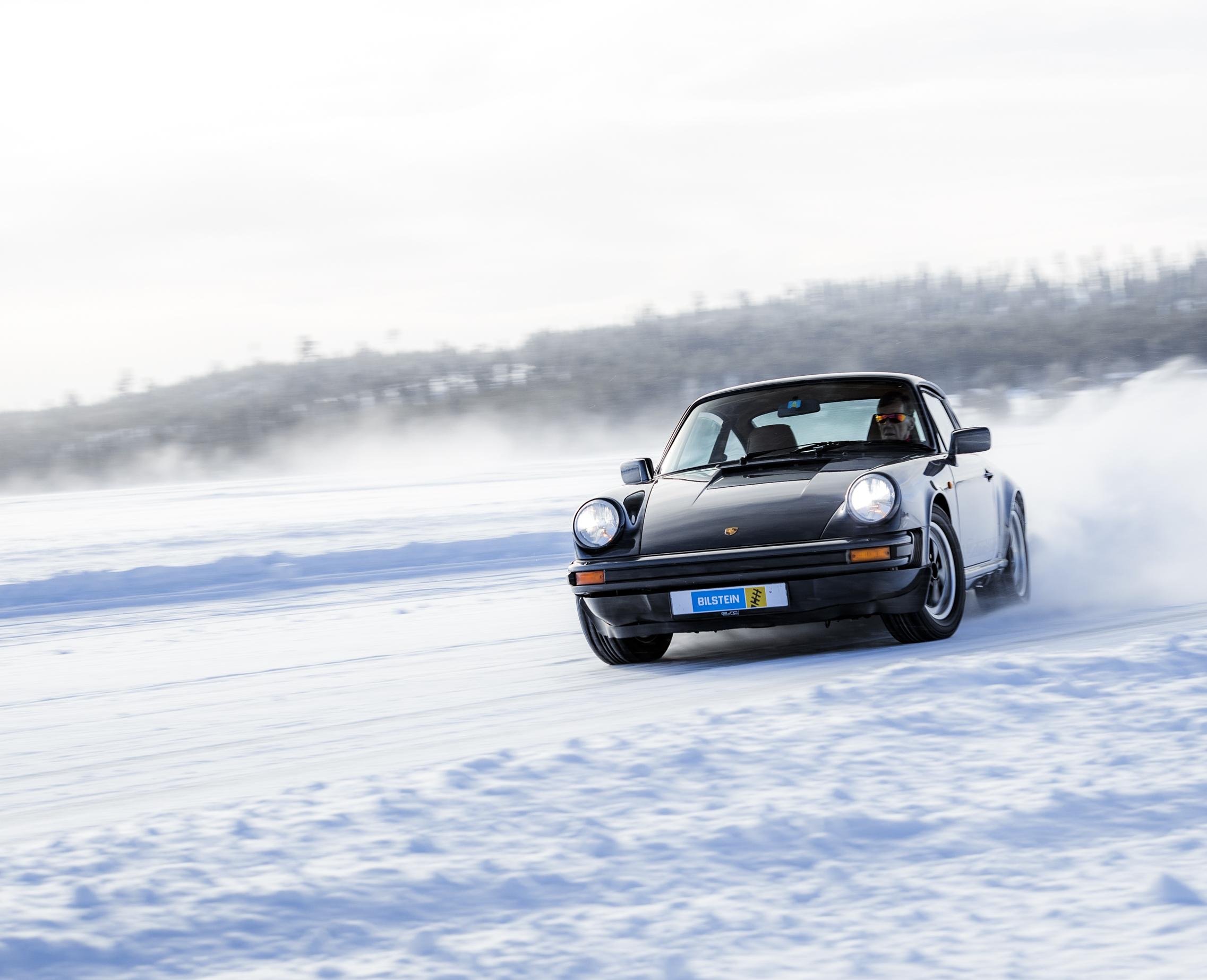 Walter R?hrl driving a black Porsche Oldtimer on a frozen lake in Sweden